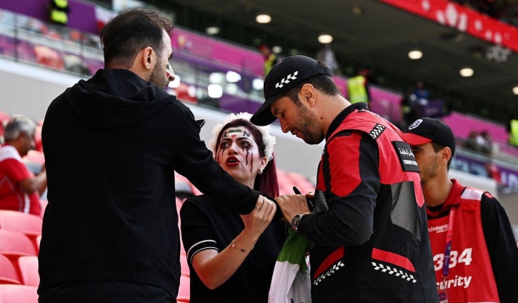 Police officers confiscate an Iran fan’s ’Women Life Freedom’ flag inside the stadium